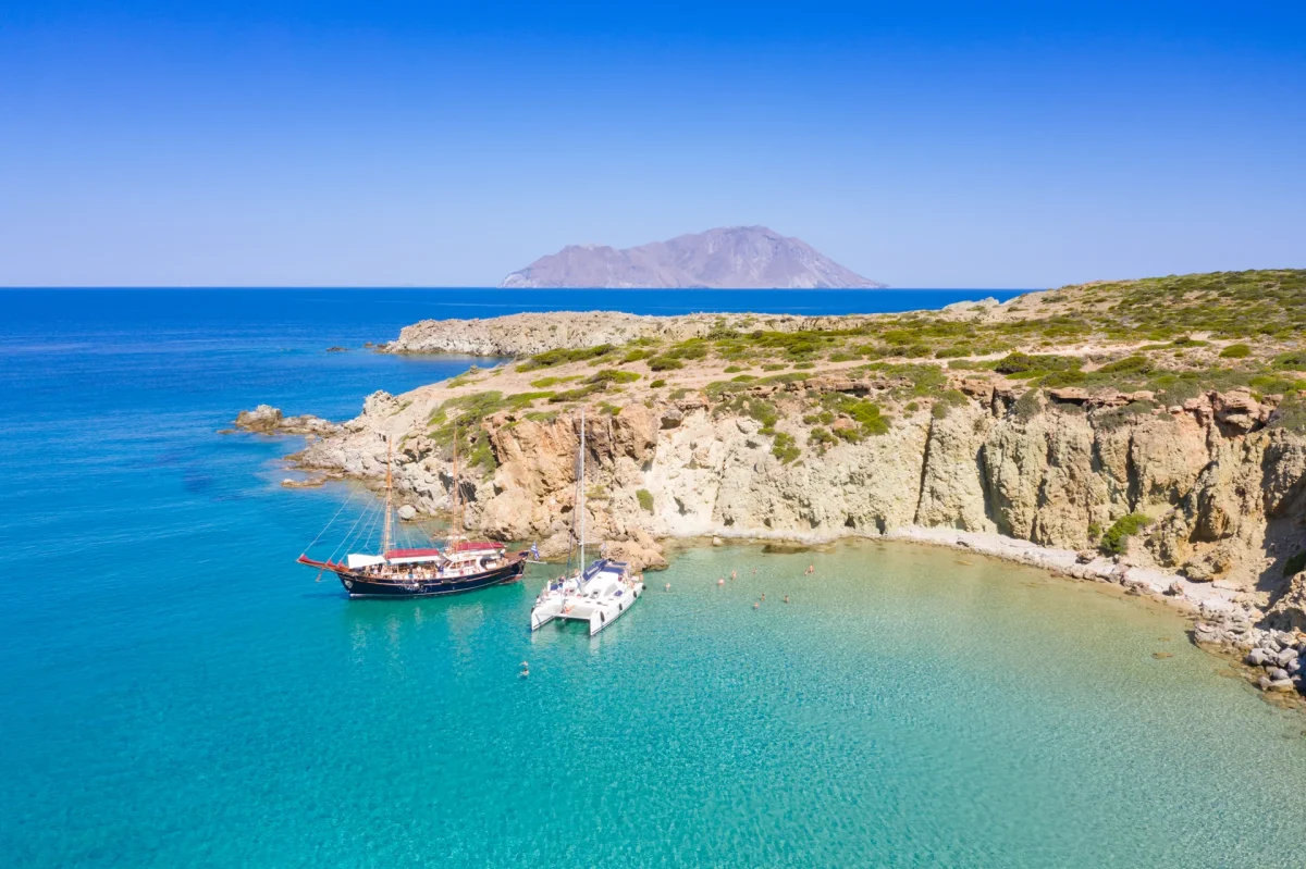 Tour boats anchored below the white cliffs of Kleftiko, Milos, seen from above