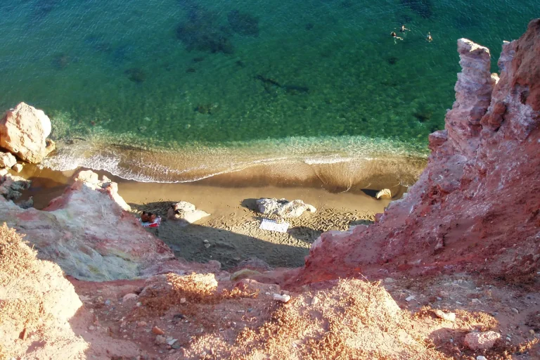 Paleochori beach in Milos, a long sand and pebble beach under red and yellow volcanic cliffs